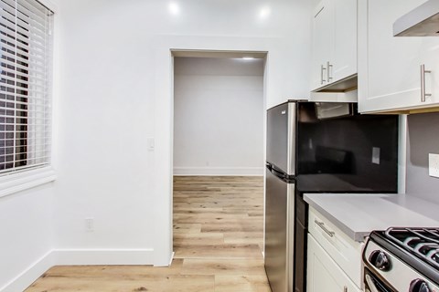 A kitchen with a stainless steel refrigerator and a wooden floor.