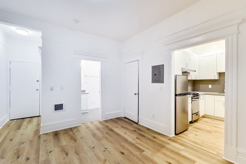 A kitchen with white cabinets and a wooden floor.