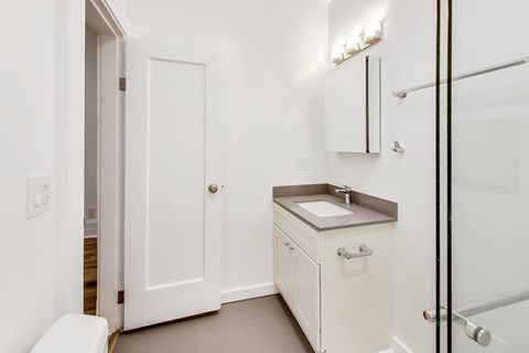 A white bathroom with a toilet, sink, and mirror.