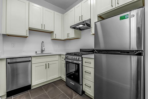 A kitchen with white cabinets and a stainless steel refrigerator.