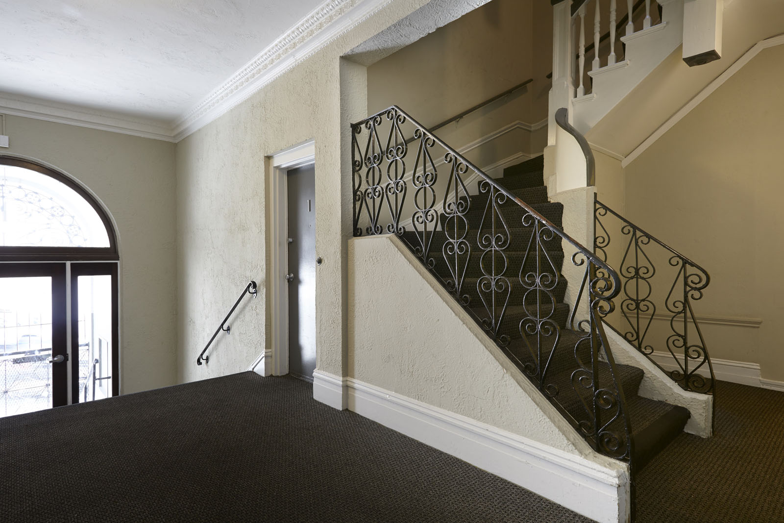 A staircase with a metal railing and a carpeted floor.