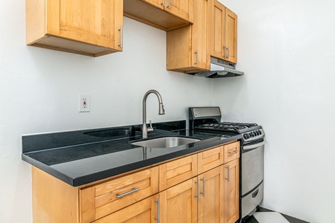 A kitchen with wooden cabinets and black countertops.