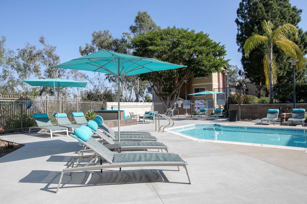 a pool with lounge chairs and umbrellas next to a swimming pool