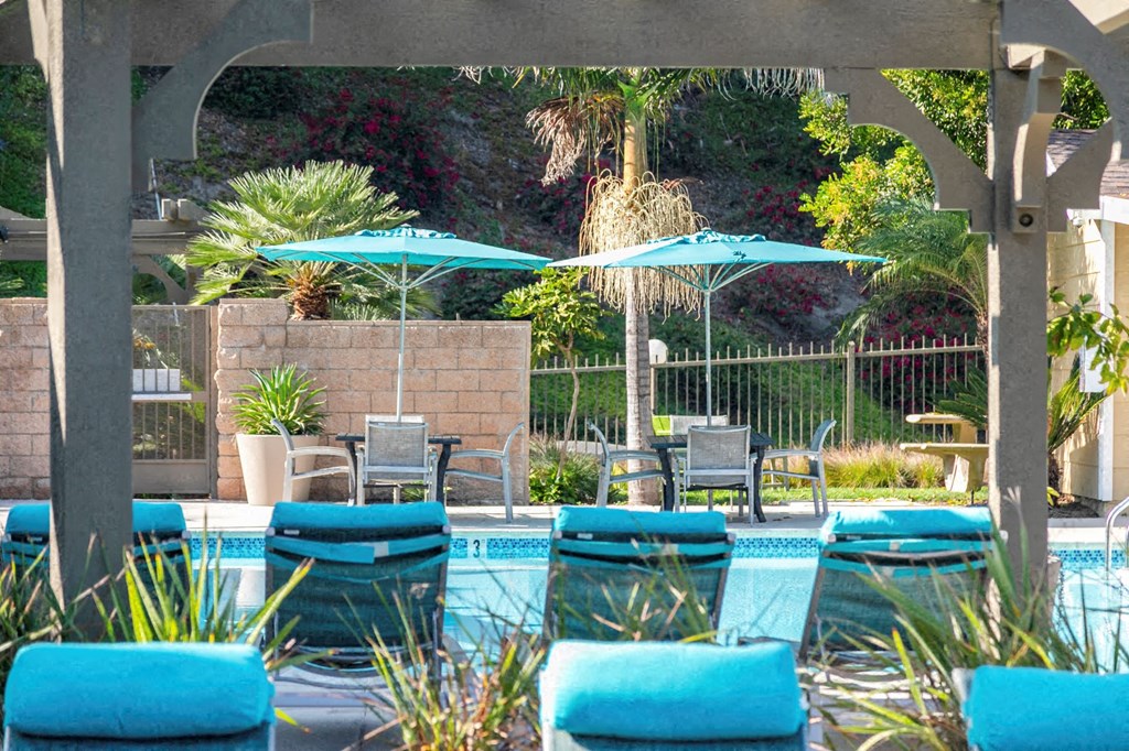 a swimming pool with blue chairs and umbrellas