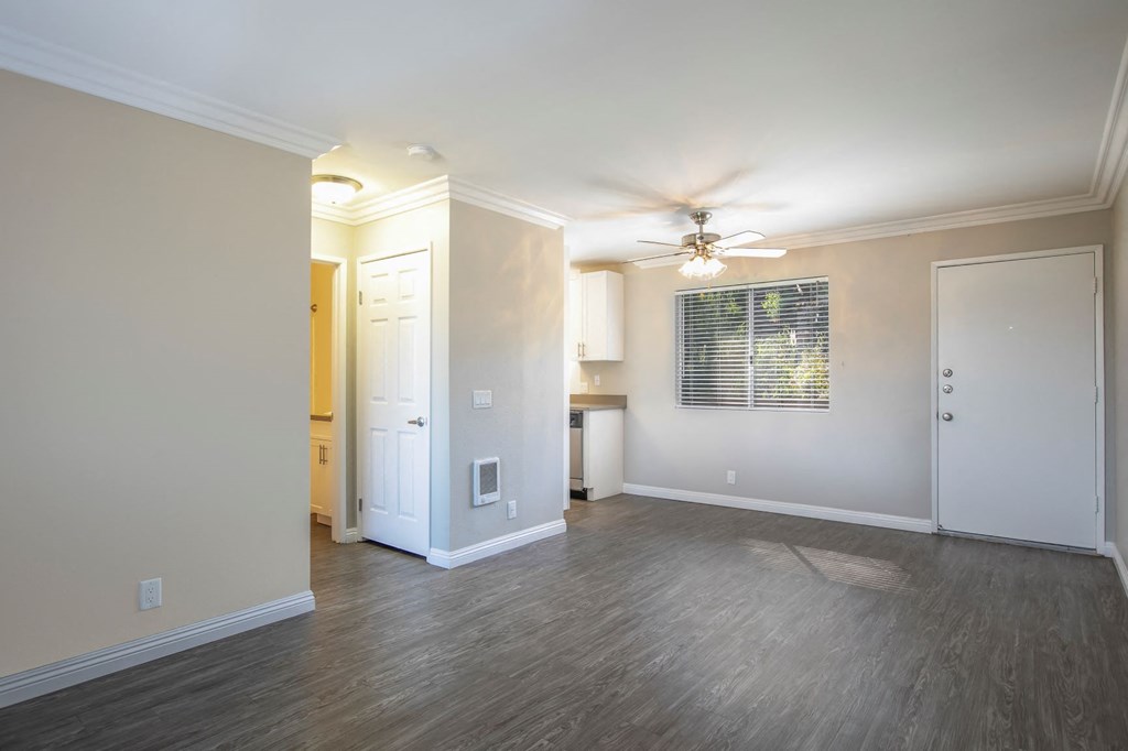 a living room with a ceiling fan and a door to a kitchen