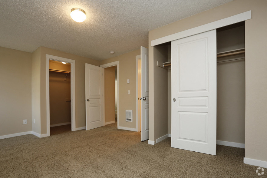 an empty living room with doors open to three closets