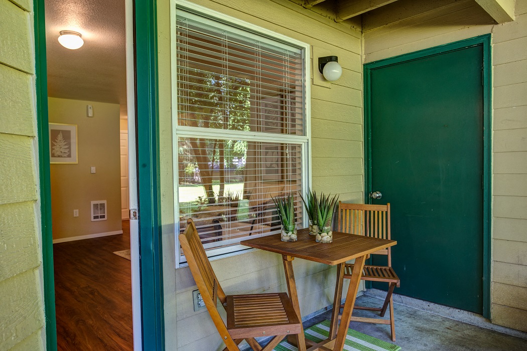 a porch with a table and chairs and a green door