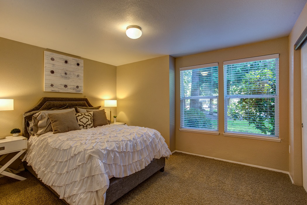 a bedroom with a bed and two windows