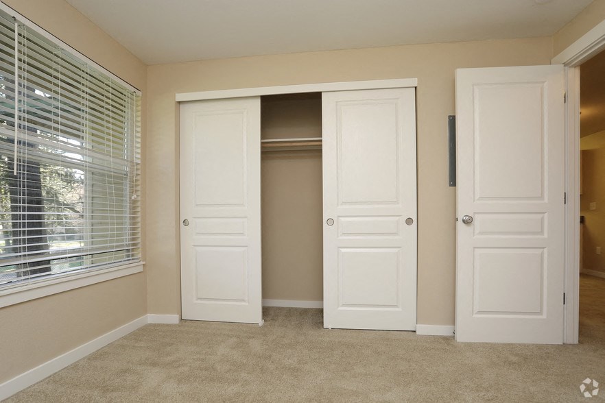 an empty bedroom with two closets and a window