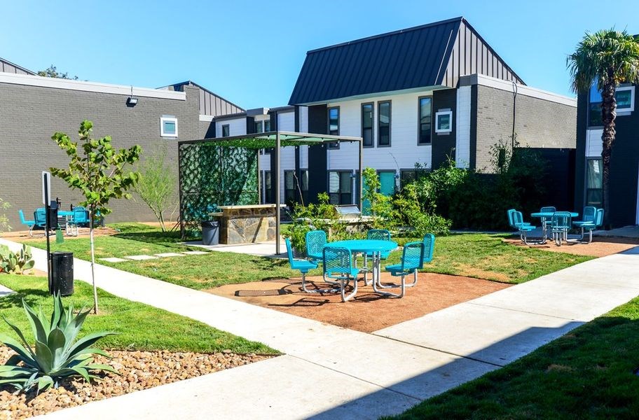 a patio with blue chairs and tables in front of a building