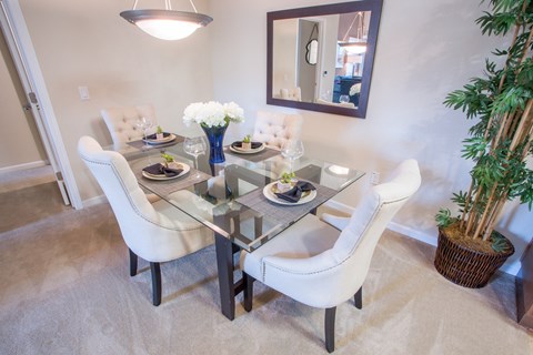 a dining room with a glass table and white chairs