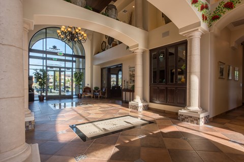 the lobby of a hotel with a large glass door and a tile floor