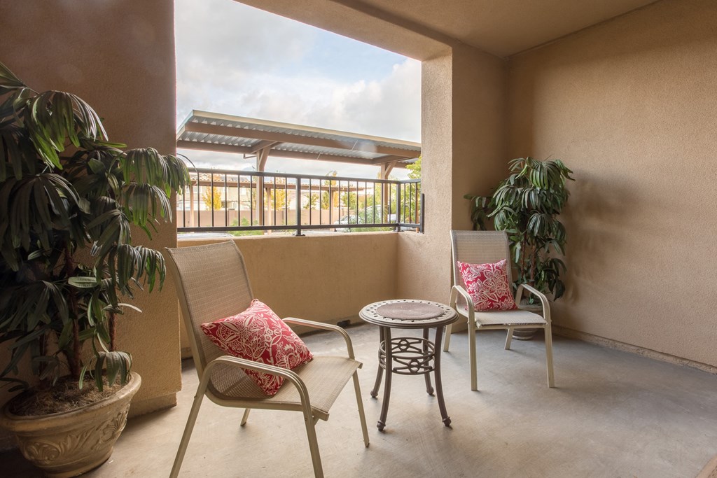a patio with chairs and a table and plants