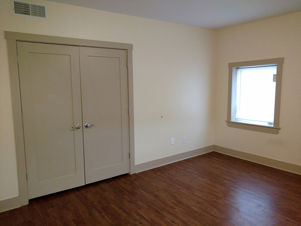 an empty room with white walls and a window and wooden floors