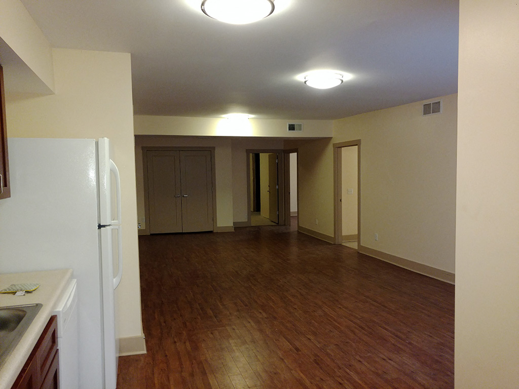 an empty kitchen and living room with a refrigerator