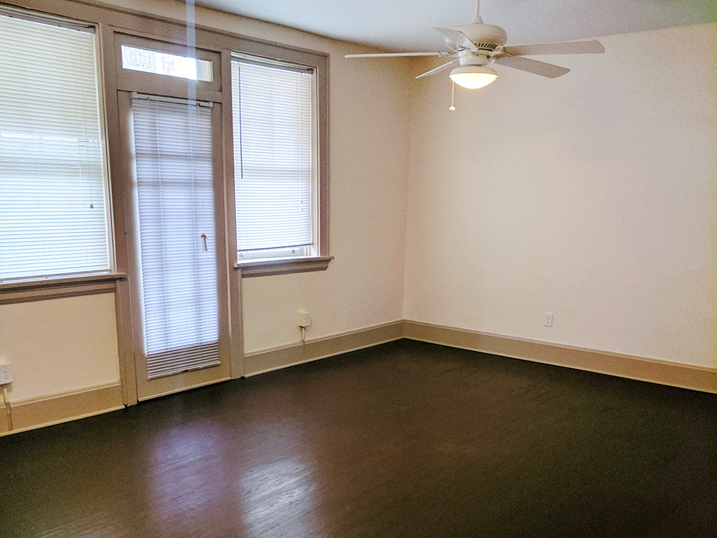 an empty room with a ceiling fan and two windows