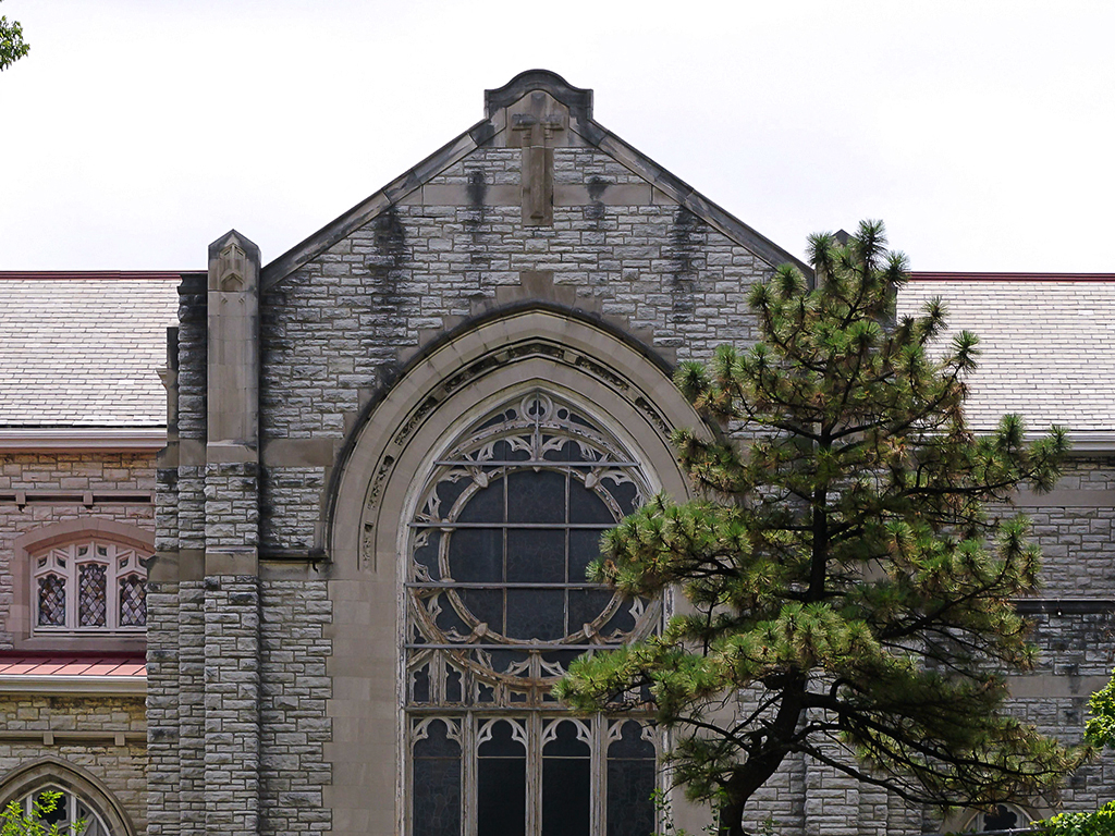 a church with a large window and a tree in front