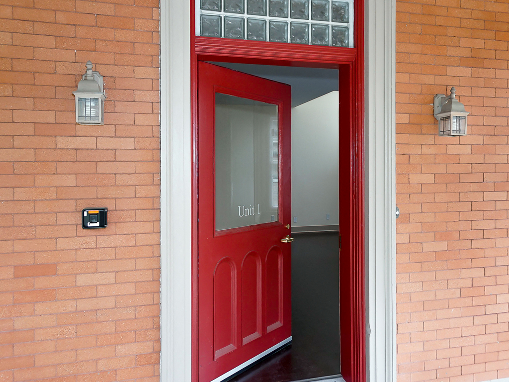 a red door that is open to a brick building
