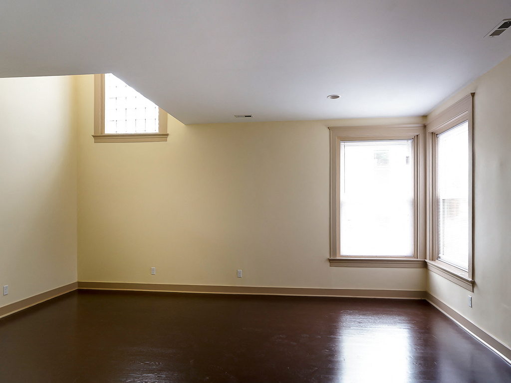 an empty living room with two windows and a wood floor