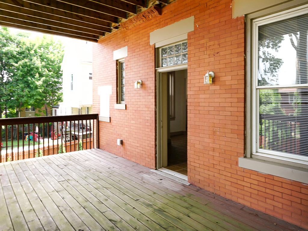 the porch of a brick house with a wooden deck