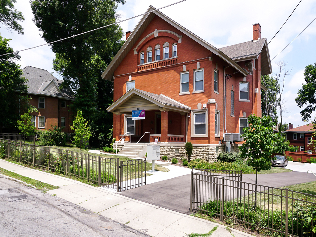 an old brick house with a sidewalk in front of it