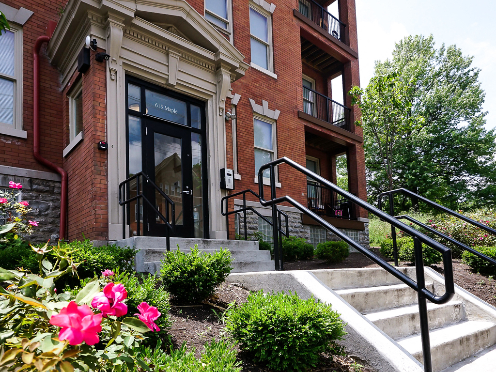 the front of a brick building with stairs and flowers