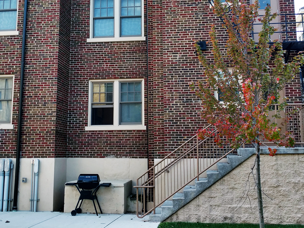 the outside of a brick building with a barbecue grill