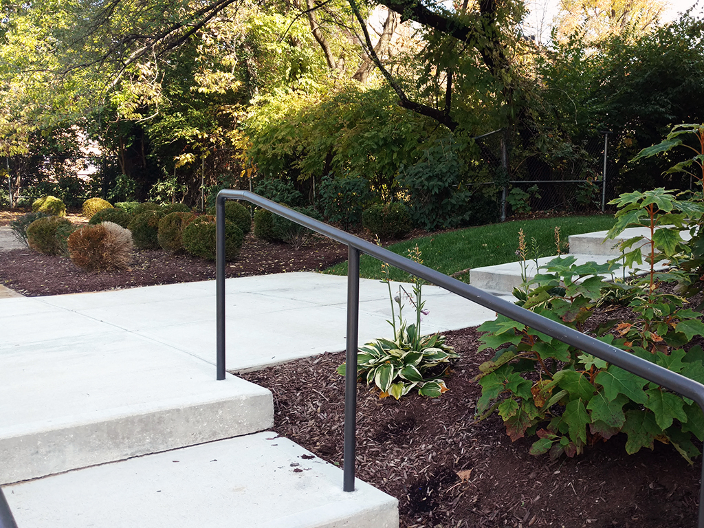 a metal railing next to some steps in a garden