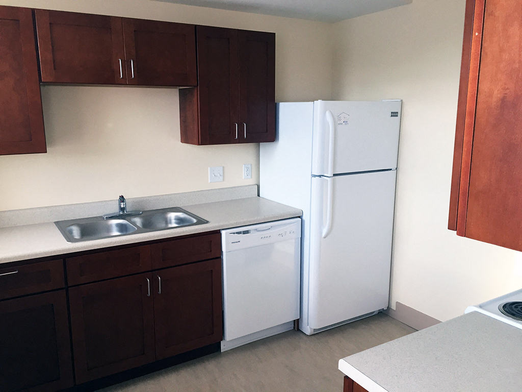 an empty kitchen with a white refrigerator and sink