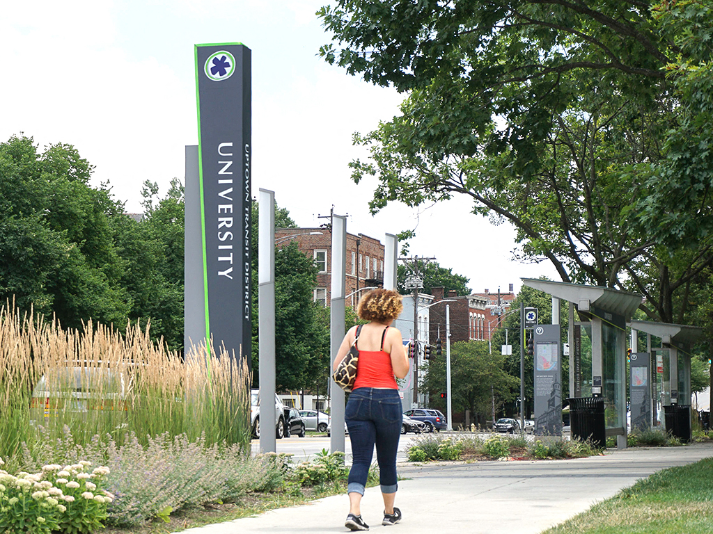 a woman walking down a sidewalk next to a sign