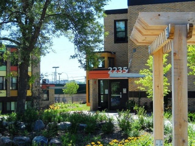 the front of a building with a porch and some trees
