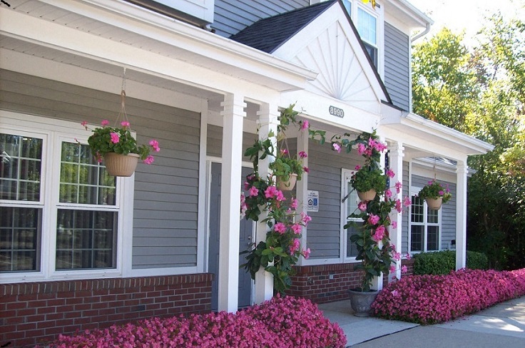 the front porch of a house with two hanging baskets of flowers