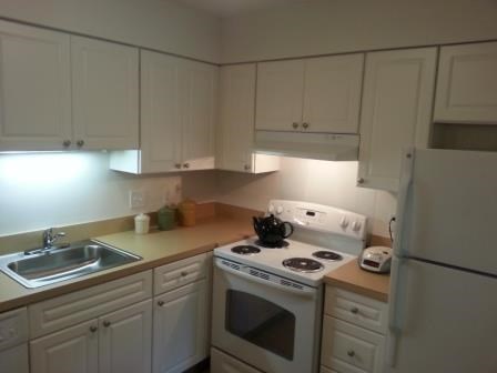 A kitchen with white appliances and cabinets.