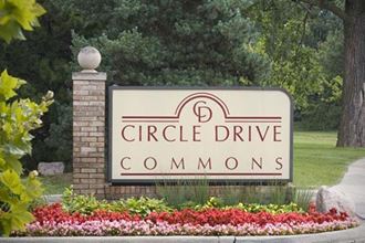 a sign for circle drive commons with flowers around it