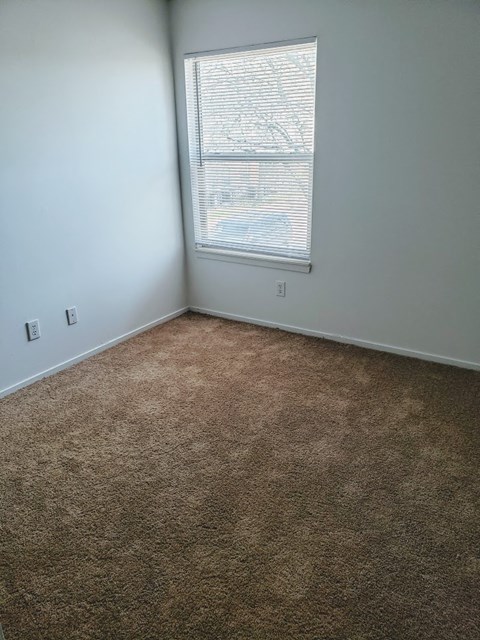 an empty room with a window and a carpet
