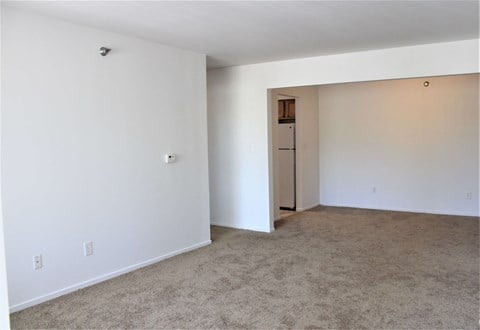 an empty living room with a white wall and carpet