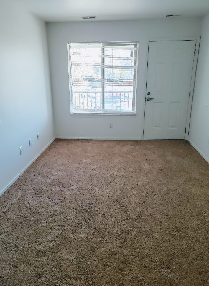 a carpeted room with a window and a door