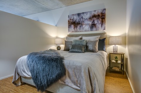 a bedroom with a bed and lamps and a painting on the wall