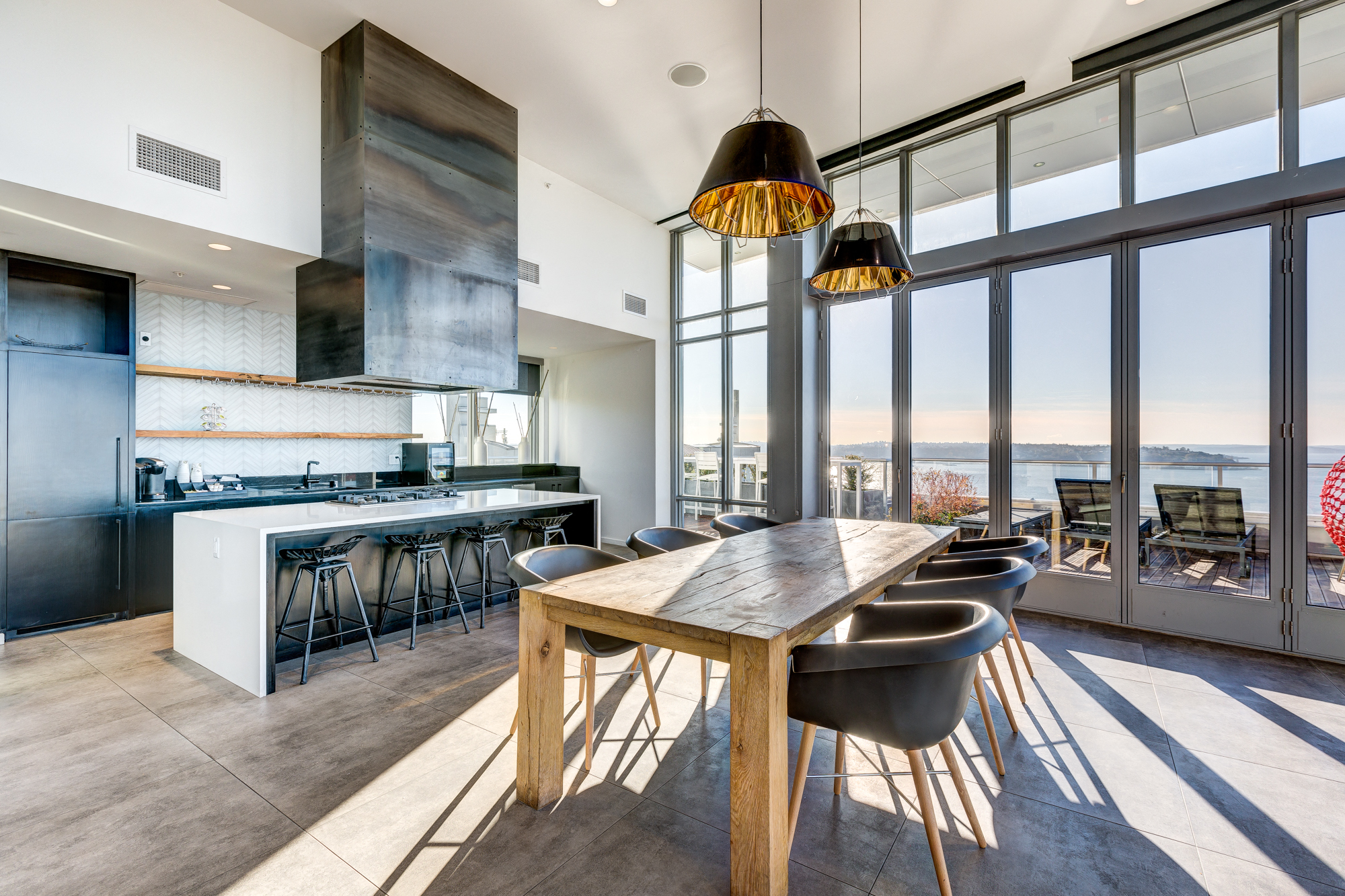 a dining area with a wooden table and chairs and a kitchen with large windows