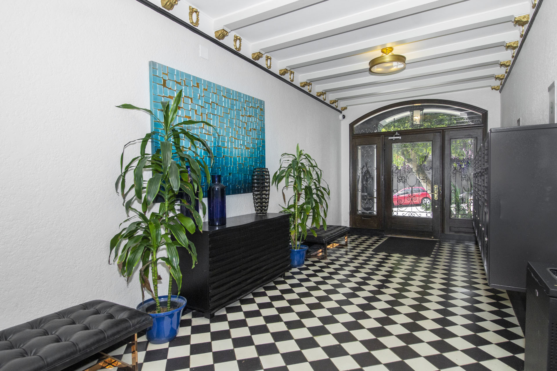 A black and white checkered floor in a room with a blue plant and a blue pot.