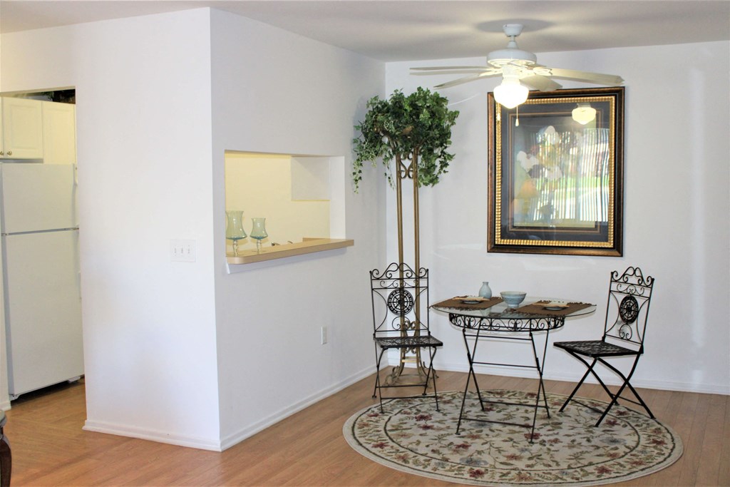 a living room with a table and two chairs and a ceiling fan
