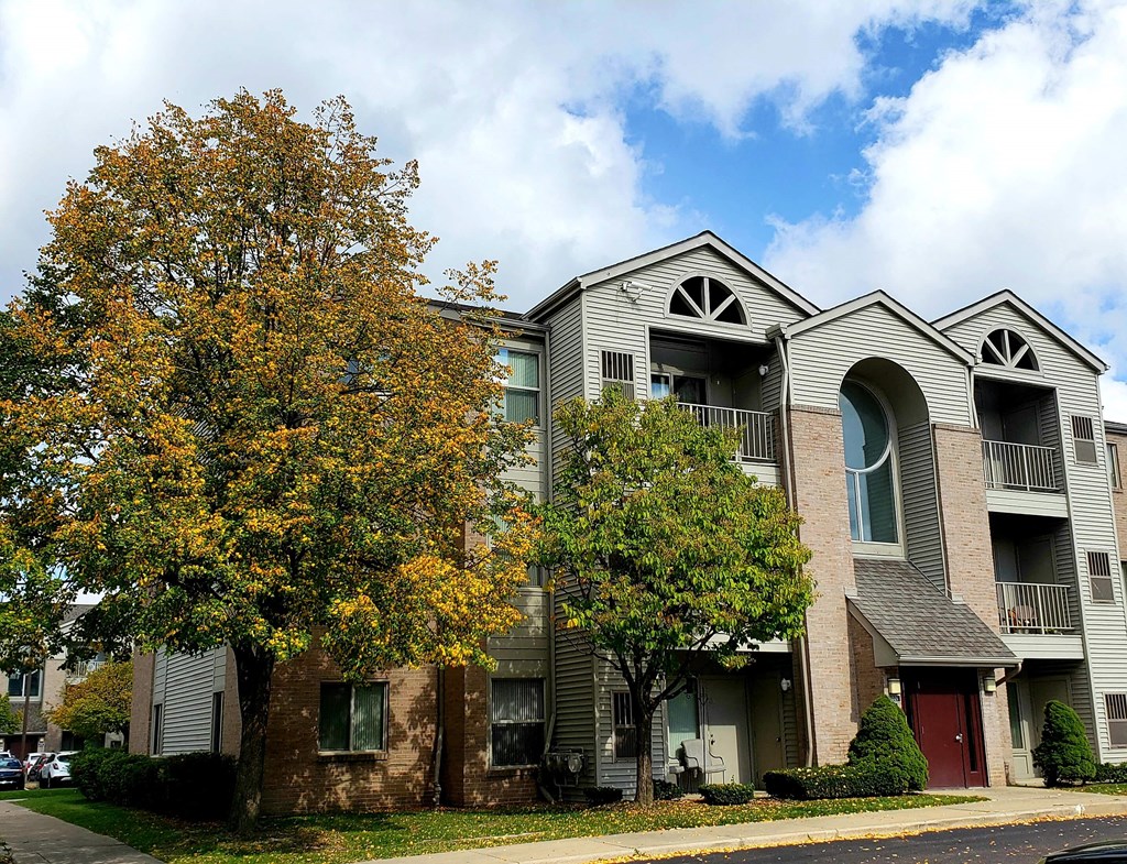 an apartment building with a tree in front of it