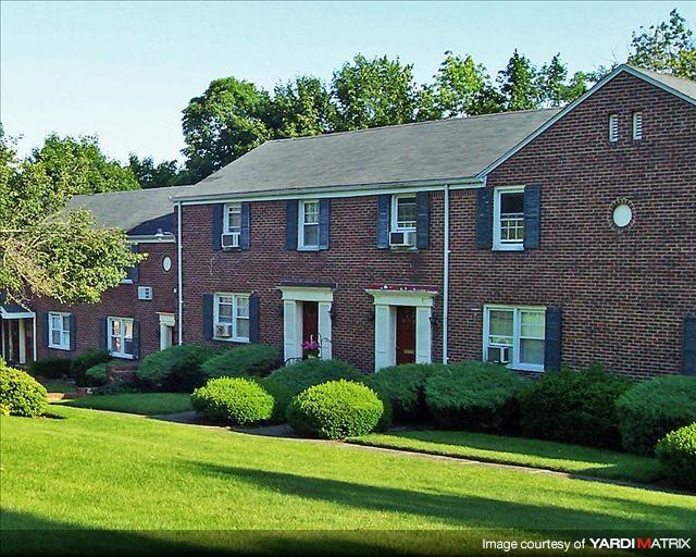 A red brick house with green bushes in front.