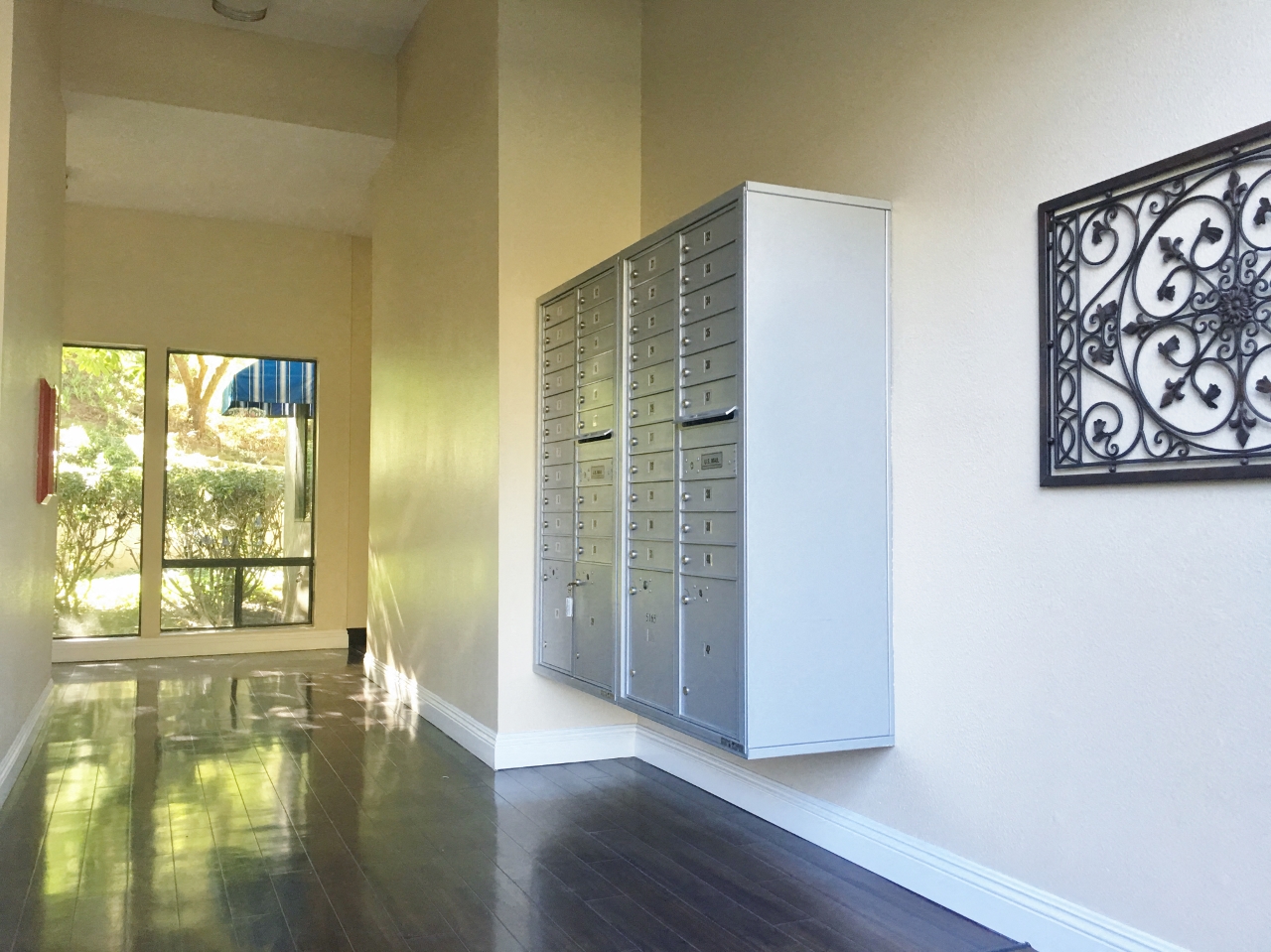 A tall white filing cabinet with drawers is in a room with a metal gate on the wall.