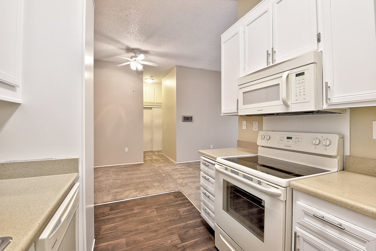 A kitchen with white cabinets and a stove top oven.