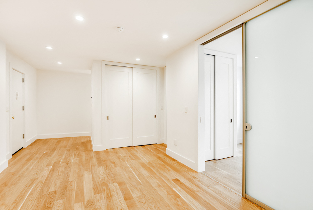 a living room with white walls and wood floors and a sliding glass door