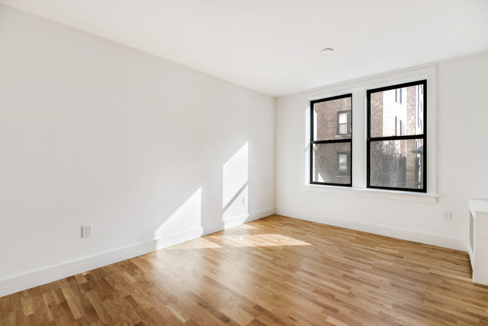 the living room of an apartment with wood floors and a window