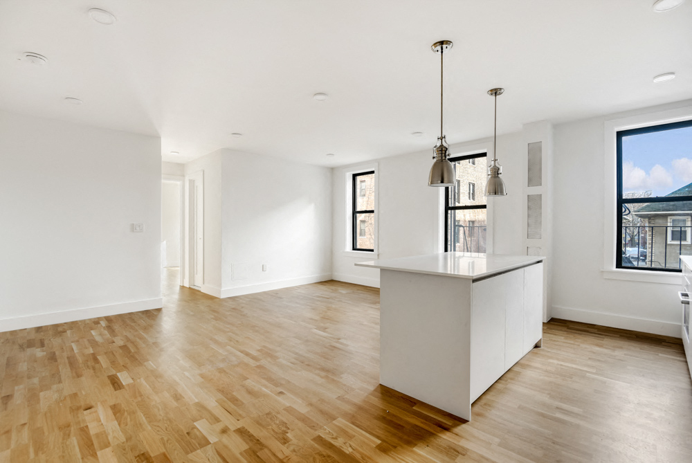 an open kitchen and living room with white walls and wood floors