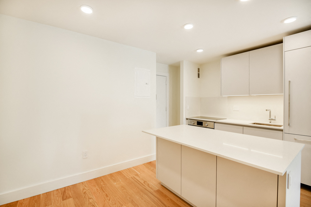 A kitchen with white cabinets and a white countertop.