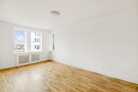 the living room of an apartment with wood floors and a window